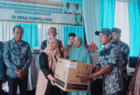 Wakil Bupati Tojo  Una-Una, Hj.Surya, S.Sos, M.Si, saat menyerahkan bantuan pembebasan lahan untuk pembangunan jaringan listrik di Desa Tombulawa, Minggu 4 Mei 2025
