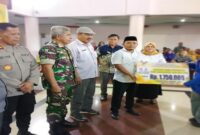Anggota DPRD Tojo Una-Una, Sutrianto menyerahkan bantuan pendidikan kepada salah seorang Mahasiswi diruang lobi kantor bupati, Jumat (1/8)