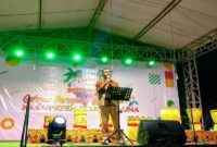 Ketua Panitia Asrin W. Soga saat menyampaikan laporan kegiatan pada pembukaan HUT Tojo Una-Una ke- 22 di Lapangan Alun-Alun Kota Bumi Mas, Kelurahan Uemalingku, Kecamatan Ratolindo pada Rabu malam, (10/12/2025).