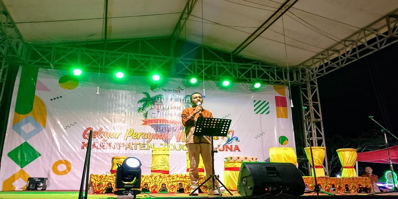 Ketua Panitia Asrin W. Soga saat menyampaikan laporan kegiatan pada pembukaan HUT Tojo Una-Una ke- 22  di Lapangan Alun-Alun Kota Bumi Mas, Kelurahan Uemalingku, Kecamatan Ratolindo pada Rabu malam, (10/12/2025).
