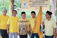 Ketua DPD II Partai Golkar Tojo Una-Una, Gusnar A. Suleman (kanan), menyerahkan  bendera pataka kepada Ketua PK Partai Golkar Ratolindo, Taslim, saat pengukuhan di Sekretariat Golkar Ratolindo, Senin (6/7/2026)